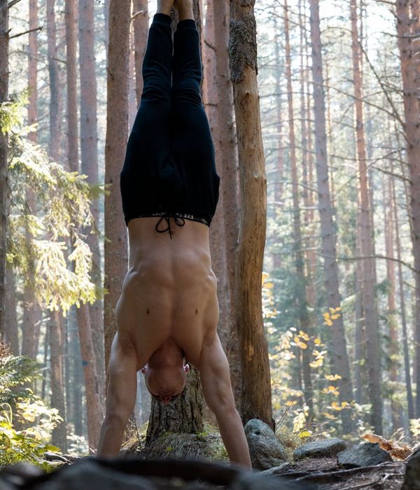 Man performing a controlled bodyweight exercise with intense focus in a dark, minimalist setting.